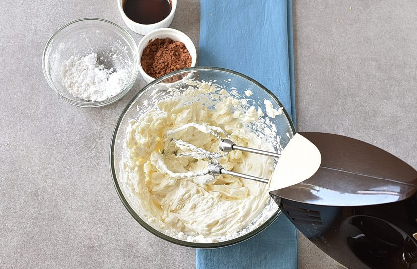 1. Этап. Шоколадный Чизкейк: Крем-чиз обязательно должен быть комнатной температуры. Взбейте сыр с 4 столовыми ложками сахарной пудры до пышности и однородности.