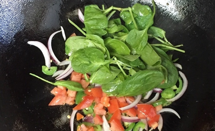 1. Этап. Домашний омлет с овощами: 2. Вымойте шпинат, нарежьте кусочками помидоры. Выложите овощи к остальным в сковороде.