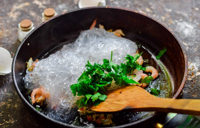 1. Этап. Лапша с креветками по-тайски: Переложите в сковороду запаренную фунчозу и добавьте нарезанную кинзу, соль и перец по вкусу.