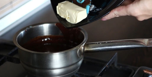 1. Этап. Пончики печеные: 5. Добавьте в глазурь сливочное масло, размешайте до однородного состояния и оставьте остужаться.