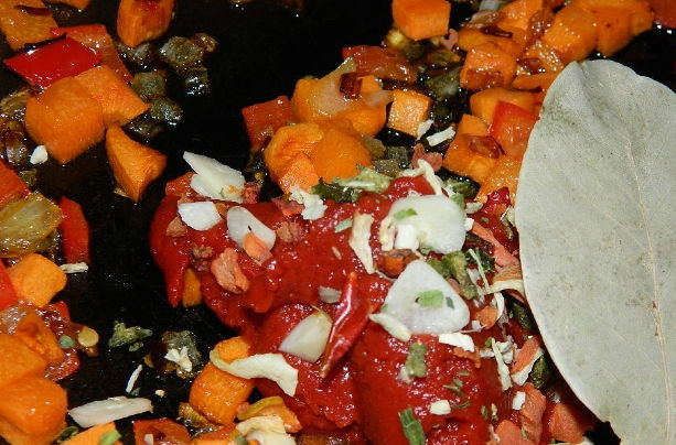 1. Этап. Томатный суп пюре с рисом: Лук чистим и режем мелкими кубиками. Морковку очищаем и также нарезаем кубиками. Перчик очищаем от семечек, режем так же — кубиками. Все вместе выкладываем на разогретую сковороду, смазанную маслом. Обжариваем 15 минут, затем добавляем томатную пасту, лавровый лист, специи и рубленый чеснок. Тушим пару минут.