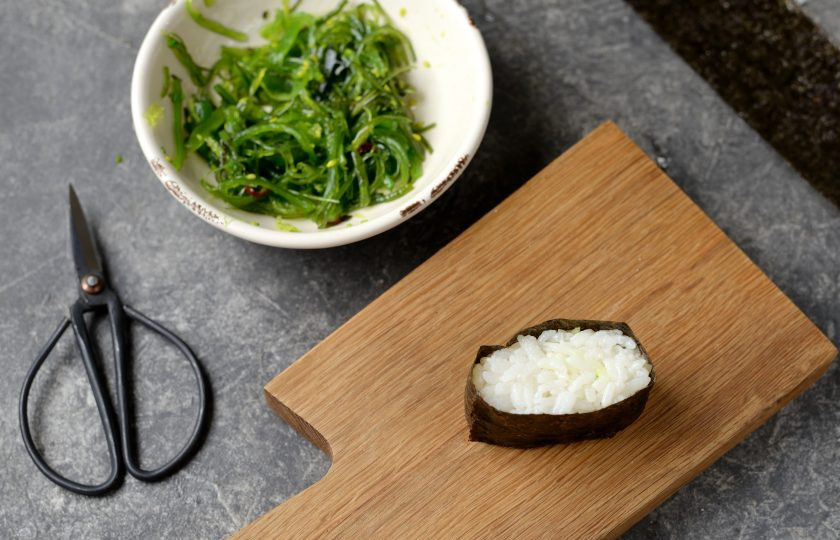 1. Этап. Роллы с чукой: Если роллы вы не умеете крутить совсем, можно приготовить гунканы, это намного проще и быстрее. Для этого нужно смочить ладони в холодной воде, взять горсть риса, склеить из него шарик, а потом придать ему овальную форму и завернуть в полоску нори.