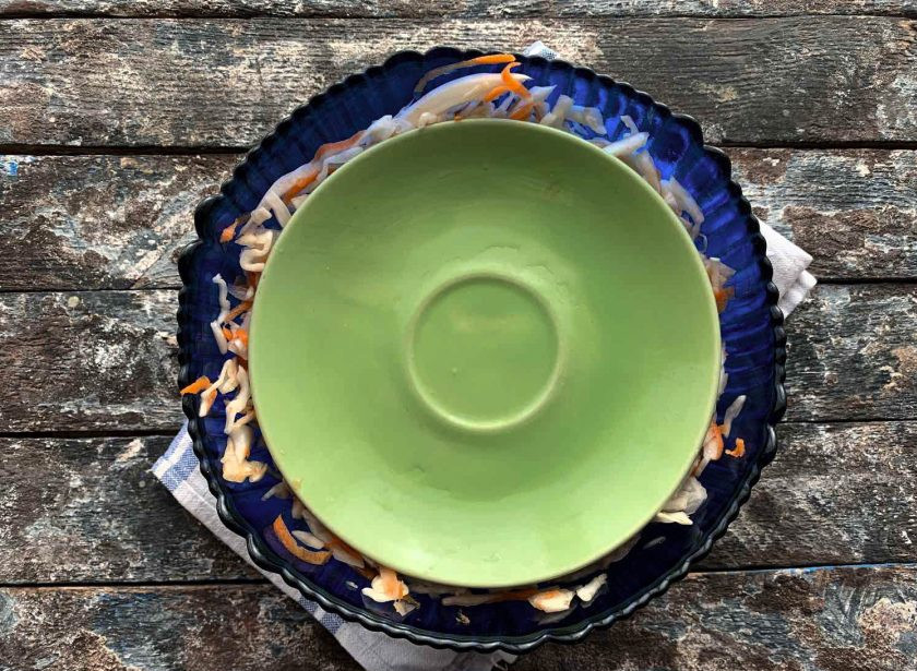 1. Этап. Квашеная капуста с изюмом: Выложите оставшуюся капусту, сверху закройте блюдцем и поставьте гнет. Оставьте на 3 дня при комнатной температуре.