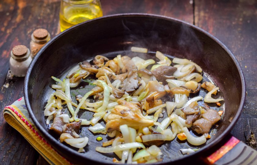 1. Этап. Салат из вешенок и кальмаров: Жарьте грибы и лук несколько минут с добавлением растительного масла.