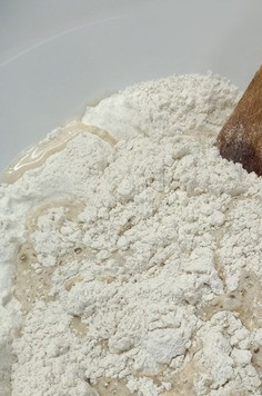 1. Этап. Батон и булочки с изюмом: Дрожжи растворить в теплой воде, в миске смешать оба вида муки, добавить соль, вылить дрожжевую смесь. Если вы будете печь с закваской, то последовательность замеса будет такой, - обе муки соединить, дрожжи раскрошить, влить половину указанного количества воды, добавить закваску (если закваска у вас сухая, то добавляем 20 гр), перемешать, влить оставшуюся воду.