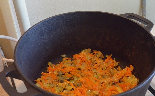 1. Этап. Свиные ребрышки с картошкой в казане: 4. Разогрейте казан с небольшим количеством масла. Выложите лук с морковью и чесноком, обжарьте 3-5 минут, помешивая.