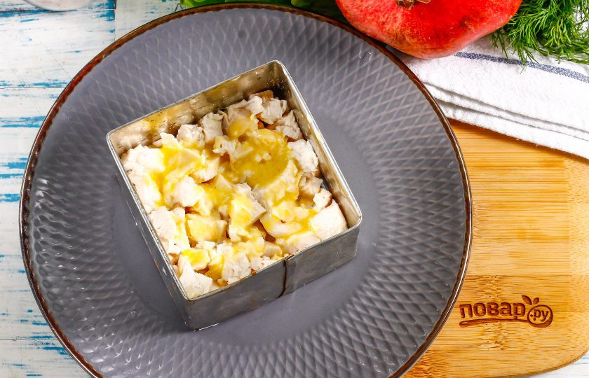 1. Этап. Салат Мужские слезы с гранатом: Нарежьте отварное куриное филе мелкими кубиками и выложите в кулинарный квадрат для приготовления салатов. Посолите и смажьте майонезом любой жирности.