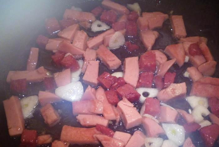 1. Этап. Омлет с колбасой: В сковороду наливаем растительное масло и обжариваем на нем колбасу и чеснок.