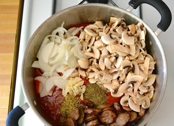 1. Этап. Макароны с сосисками и грибами в томатном соусе: 5. Выложите к хорошо обжаренным сосискам томатный соус, лук, грибы, чеснок, сушеные травы, перемешайте хорошенько.