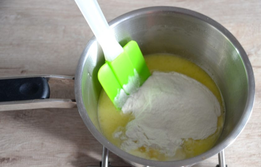 1. Этап. Профитроли без глютена: Снова поставьте сотейник на небольшой огонь, всыпьте разом всю рисовую муку и интенсивно размешайте до равномерной консистенции. Снимите с огня, слегка остудите.