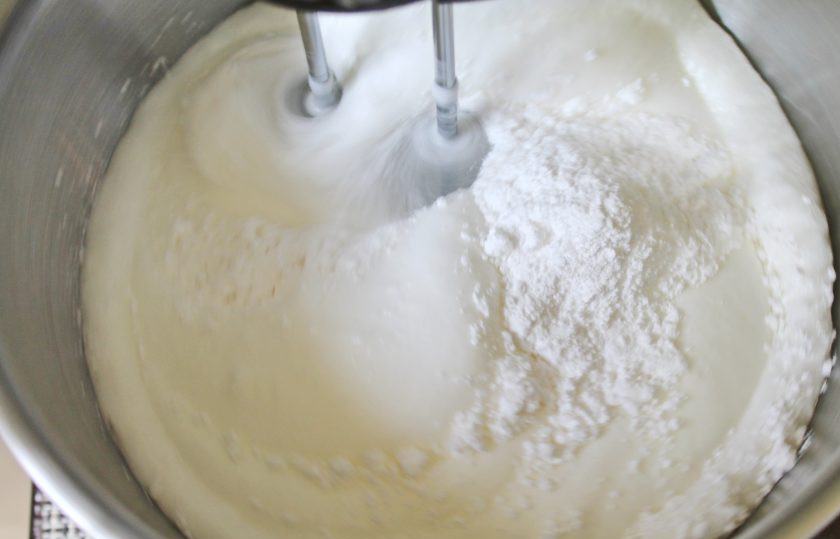 1. Этап. Меренговый рулет с клюквой: Увеличьте скорость взбивания и влейте лимонный сок. Постепенно всыпайте сахарную пудру.