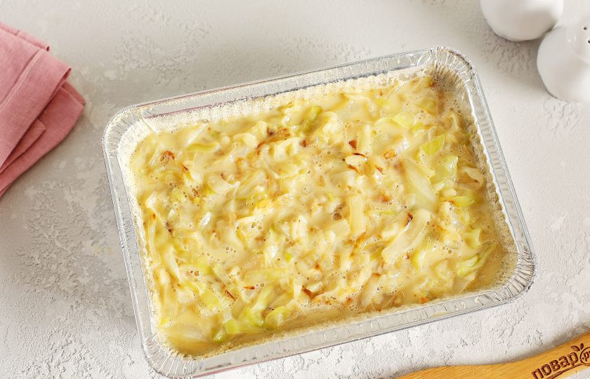 1. Этап. Белокочанная капуста в сыре в духовке: Форму для запекания смажьте маслом. Дно и бока посыпьте сухарями или манкой. Соедините тушеную капусту и заливку. Перемешайте и выложите в форму.