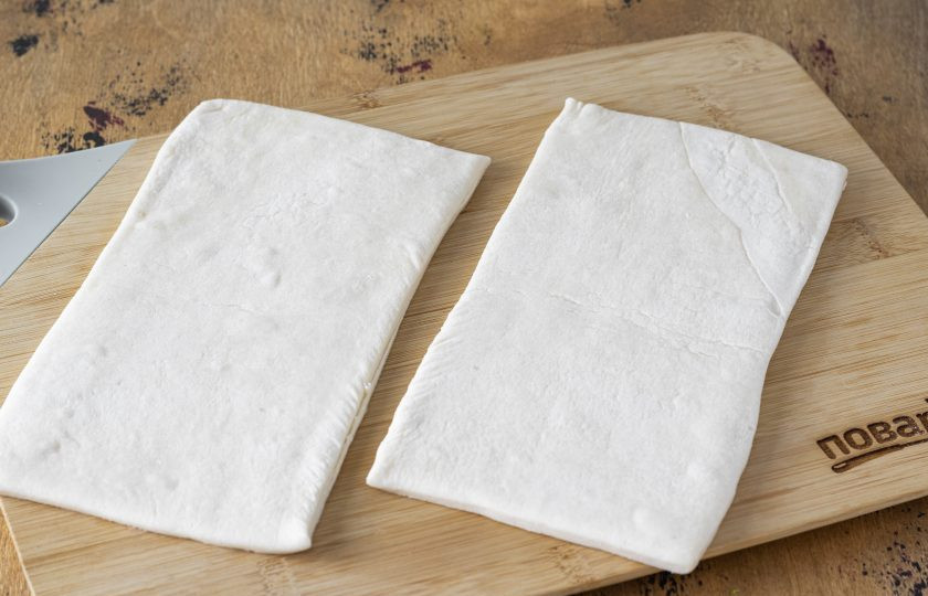 1. Этап. Слойки с консервированными персиками: Разделите каждый пласт теста пополам. Немного раскатайте прямоугольники.