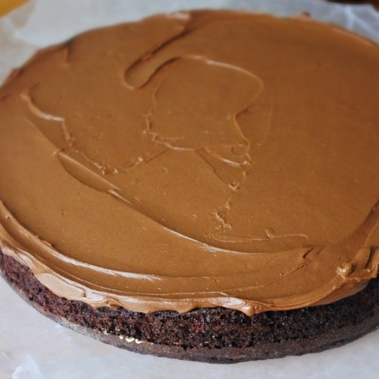 1. Этап. Кофейный торт: Берем бисквит, равномерно распределяем по нему примерно треть шоколадного крема для торта.