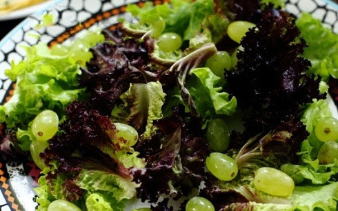 1. Этап. Салат с ветчиной и камамбером: Выкладываем на тарелки тщательно промытую и подсушенную зелень и ягодки винограда. Если виноград крупный, его можно разрезать.