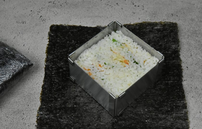 1. Этап. Суши сэндвич с креветкой: Выложите сверху оставшуюся половину риса (57-60 граммов) и хорошо придавите его ложкой, чтобы начинка уплотнилась.