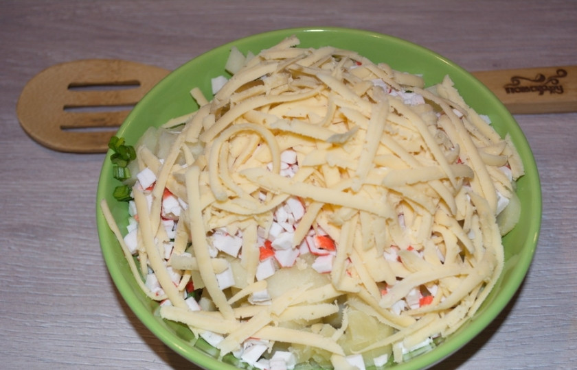 1. Этап. Салат Уральские самоцветы: Натрите на терке твердый сыр. Добавьте его в салатник.