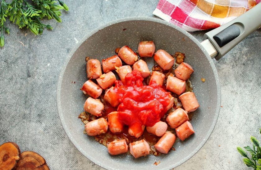 1. Этап. Сосиски в томатном соусе с рисом: Добавьте к сосискам в сковороду томаты в собственном соку и перемешайте.