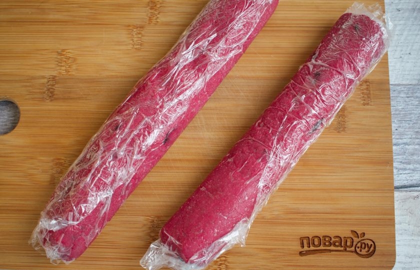 1. Этап. Свекольное печенье: Муку, соль и разрыхлитель просейте через сито. Добавьте сахар, молоко, сливочное масло, свекольный сок и вяленую клюкву, замесите однородное тесто. Разделите его на две части. Скатайте колбаски, заверните их в пищевую пленку, поместите в холодильник на 30 минут.