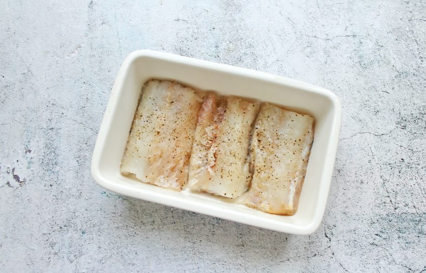 1. Этап. Пикша в сливочном соусе: Филе сполосните, обсушите бумажным полотенцем и разрежьте на порционные куски. Рыбу посолите, поперчите и выложите в форму, смазанную растительным маслом.