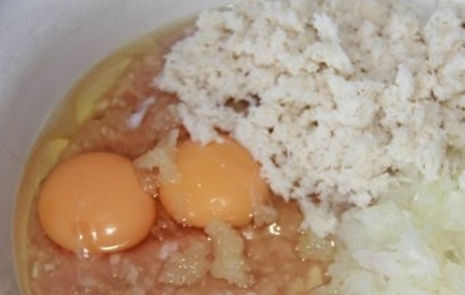 1. Этап. Куриные котлеты в томатном соусе: Измельчите чеснок и одну луковицу. Смешайте с куриным фаршем. Добавьте в фарш размоченный в молоке хлеб и два яйца. Посолите и хорошо перемешайте.