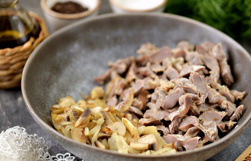 1. Этап. Бюджетный салат с куриными желудками и жареными грибами: Остывшие желудки нарежьте соломкой, переложите в глубокую миску, добавьте обжаренные грибы.