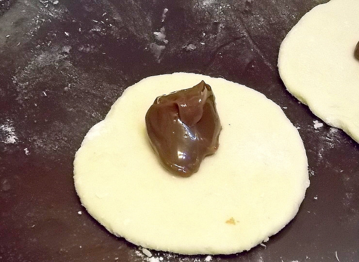 1. Этап. Творожные булочки со сгущенкой: Раскатайте с лепешку толщиной 6 мм. Положите на середину одну чайную ложку сгущенки.