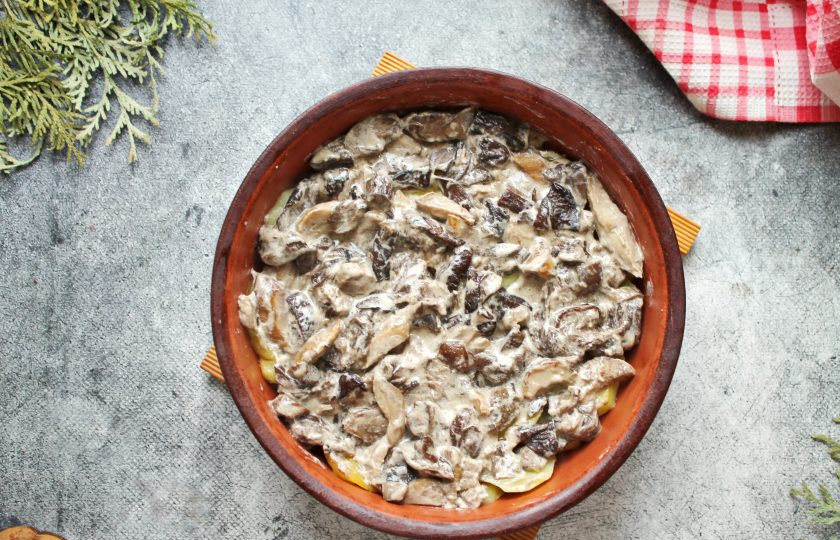 1. Этап. Грибы по-деревенски: Переложите грибы в форму с картофелем и равномерно распределите.