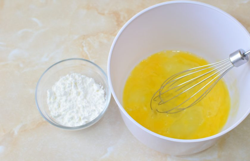 1. Этап. Французский крем для эклеров: Яйца разбейте в чашу и вмешайте к ним крахмал и ванилин. Можно добавить чуть молока из общего количества.