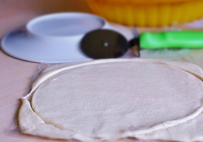 1. Этап. Закусочная пицца на слоеном тесте: 2. Кладу широкую тарелку на тесто, и по ее форме вырезаю необходимый кусочек.