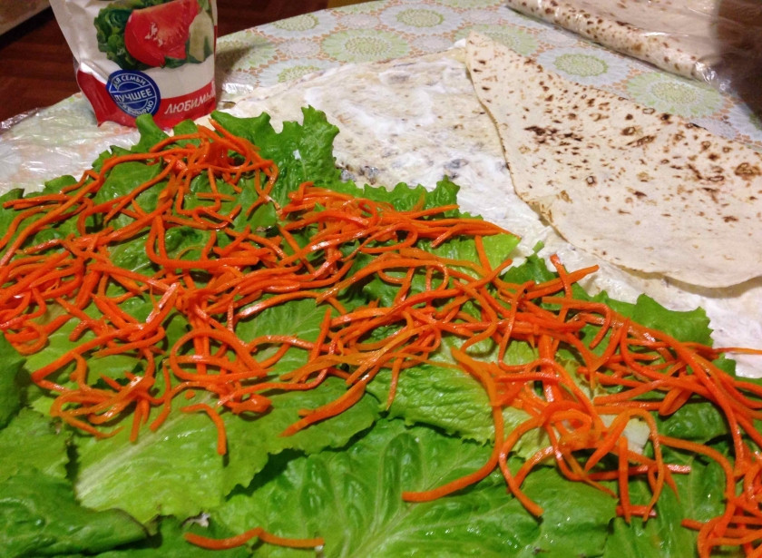 1. Этап. Рулет из лаваша с корейской морковкой: Начинаем собирать рулет: лаваш разложите и смажьте майонезом слегка, чтобы он не ломался. Затем на одну его половину выложите листья салата, поверх - морковку корейскую.