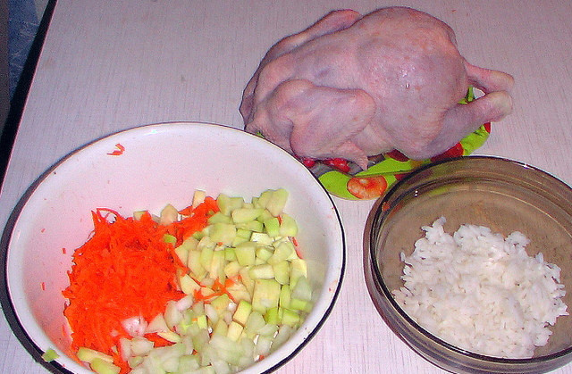 1. Этап. Курица в рукаве, фаршированная рисом: 2. Рис нужно отварить в подсоленной воде до полуготовности. Остудить немного. Тем временем можно заняться овощами. Морковь вымыть, очистить и натереть на терке. Кабачок как следует вымыть, при необходимости удалить кожуру и нарезать мелкими кубиками.