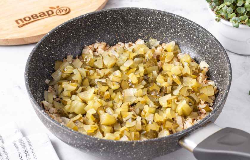 1. Этап. Постный суп Калья: Соленые огурцы порежьте на кубики такого же размера, что и лук. Добавьте в сковороду, влейте рассол или воду, потушите 10 минут.