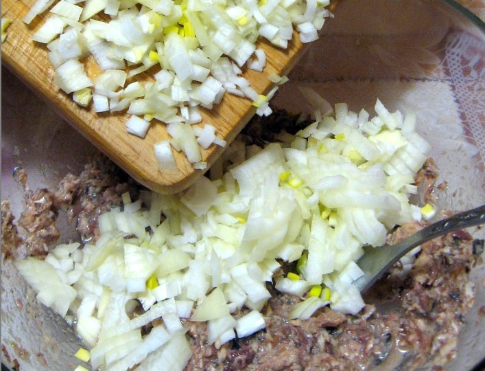 1. Этап. Рыбные котлеты из консервы: Репчатый лук чистим и нарезаем на мелкие кубики, затем выкладываем его в миску с рыбой и хорошенько перемешиваем.