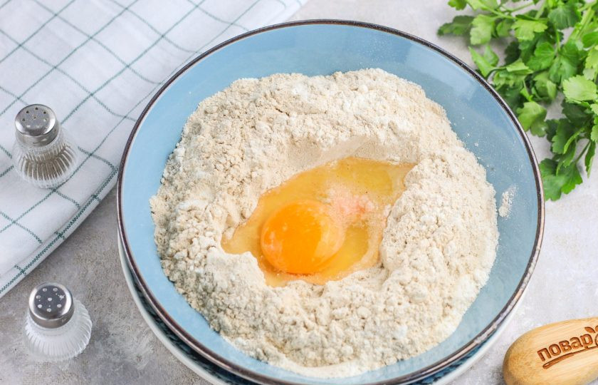 1. Этап. Вареники на гречневой муке: Перемешайте между собой оба вида муки и отделите одну четверть для раскатки. Три четверти всыпьте в глубокую емкость, сделайте в муке лунку и добавьте соль. Вбейте куриное яйцо и влейте теплую воду либо молоко любой жирности.