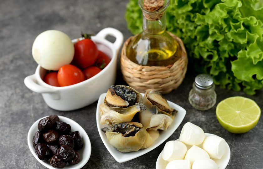 1. Этап. Салат с рапанами: Подготовьте необходимые ингредиенты. Рапаны заранее разморозьте, помойте и обсушите латук и помидоры, почистите и промойте лук.