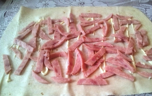 1. Этап. Рулет из лаваша с сыром, ветчиной и морковкой: Выкладываем лаваш на рабочую поверхность и немного смазываем майонезом. Затем выкладываем нарезанную соломкой ветчину.