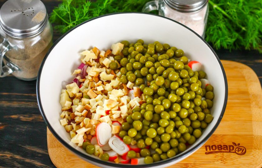 1. Этап. Салат с сыром косичка и крабовыми палочками: Консервированный горошек откиньте на дуршлаг, сливая маринад. Добавьте горошины в емкость. Сыр 