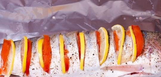 1. Этап. Судак, запеченный в фольге целиком: 5. Лист фольги смажьте растительным маслом, выложите на него рыбку. В отверстия разместите ломтики лимона и помидора.