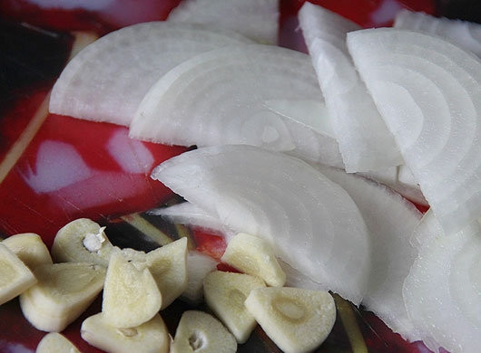 1. Этап. Щавелевый крем-суп: Лук и чеснок очистите от шелухи. Репчатый лук нарежьте полукольцами, а чеснок — тонкими пластинками.