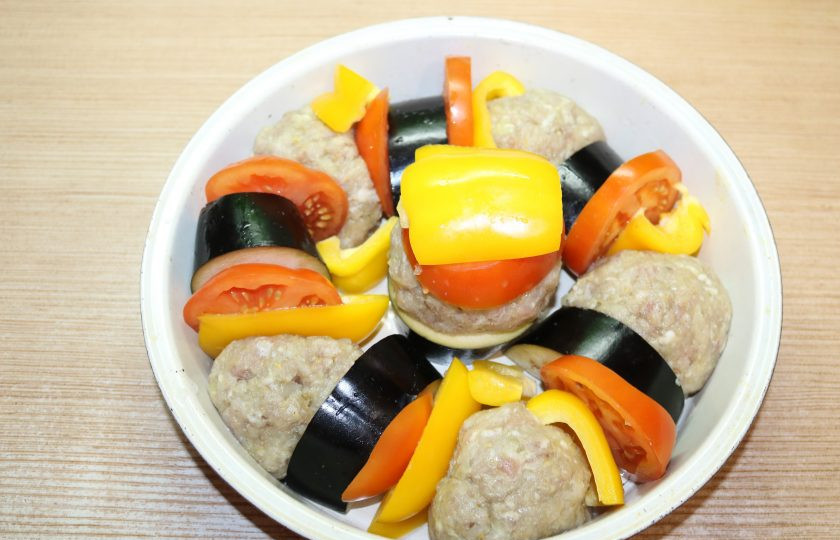 1. Этап. Тава-кебаб: Форму для запекания смажьте маслом. Из фарша сформируйте колобки, выкладывайте в форму для запекания, чередуя с баклажанами, помидором и перцем. Добавьте в 150 мл воды щепотку соли, залейте овощи и мясо. Отправьте в разогретую до 180 градусов духовку.