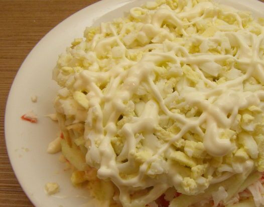 1. Этап. Крабовый салат с плавленым сыром: Выкладываем на яблоки еще четверть крабовых палочек, затем — яйца, поливаем майонезом.