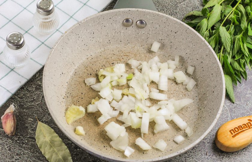 1. Этап. Закуска из куриных лапок: Очистите лук и чеснок, промойте в воде. Нарежьте лук мелкими кубиками, а чеснок пропустите через специальный пресс. Высыпьте нарезки на сковороду с растительным маслом и обжарьте на умеренном нагреве 3-4 минуты.