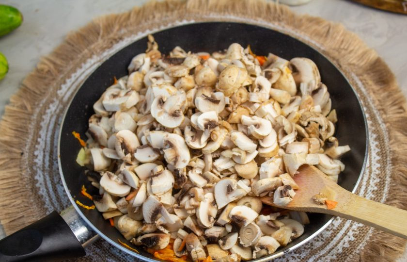 1. Этап. Лазанья из кабачков с грибами: Грибы промойте и обсушите, нарежьте на тонкие пластины и добавьте в сковороду к овощам. Готовьте, пока грибы не уменьшатся в размере и не станут мягкими.