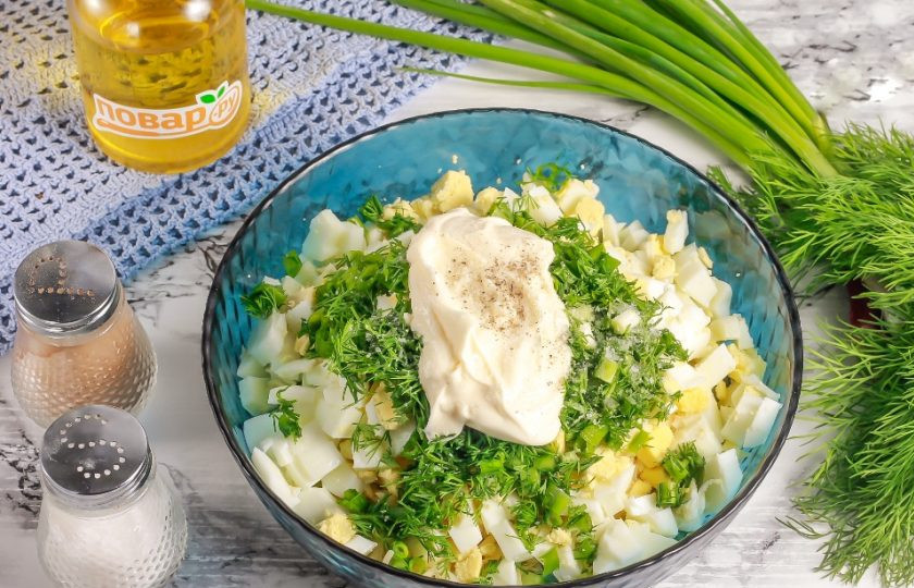 1. Этап. Салат с яйцом, огурцом, зелёным луком и сыром: Выложите майонез любой жирности, всыпьте соль и молотый черный перец. Аккуратно все перемешайте.