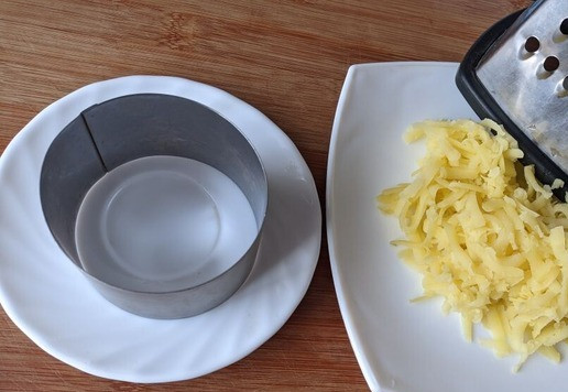 1. Этап. Салат Воевода с тунцом и редькой: Так как этот салат слоёный, то собираем его с помощью разъёмной формы или порционно с помощью шеф-кольца. Кладём кулинарное кольцо на блюдо (тарелку). Картофель чистим, трём на тёрке.