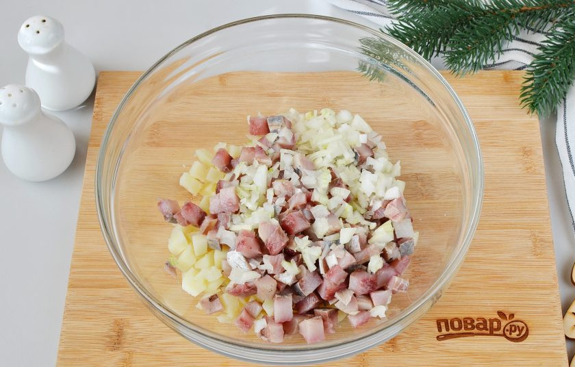 1. Этап. Салат Тигр в шубе на Новый год: Селедку разделайте, удалите голову, внутренности, кожу и косточки. Филе порежьте кубиками. Луковицу очистите и порежьте очень мелко, выложите в салатник.
