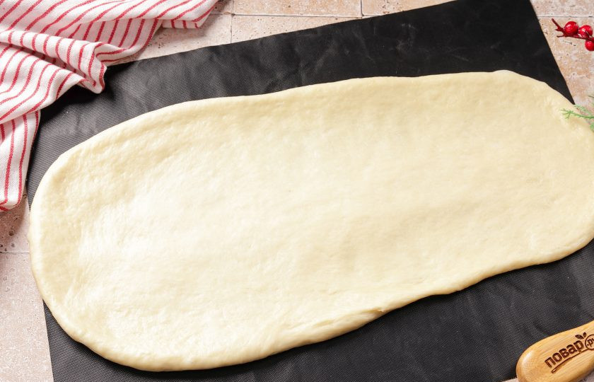 1. Этап. Новогодний пирог Змейка: Тесто раскатайте в пласт, примерно как на фото. Одна сторона должна быть чуть шире, чем другая. Толщина теста будет зависеть от того, насколько пышную вы хотите получить выпечку, а длинна раскатки от того, насколько большую змейку. Тесто пластичное и с ним очень удобно работать.