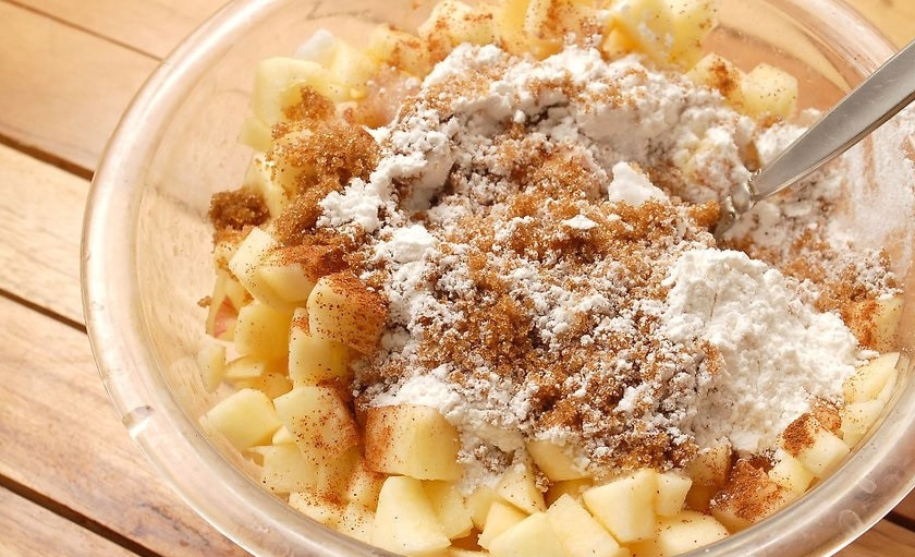 1. Этап. Простой рецепт яблочного пирога: 7. Очистите яблоки от кожуры, затем разрежьте пополам и удалите семена, нарежьте яблоки кусочками и переложите в миску. Добавьте к ним белый и коричневый сахар, муку, корицу, специи, влейте лимонный сок, перемешайте все.