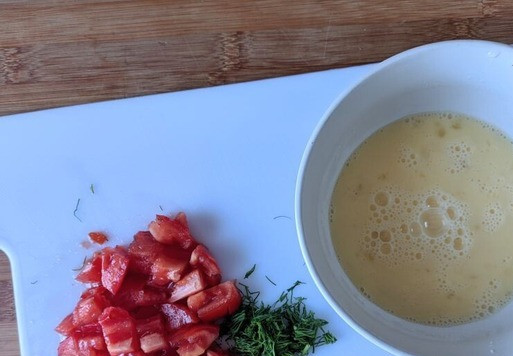 1. Этап. Большой сэндвич для всей семьи: Готовим яичницу с помидорами. В миске взбиваем яйцо, солим. Помидор режем мелкими кубиками, зелень измельчаем, у меня - укроп. Смешиваем яйца с помидорами и зеленью.